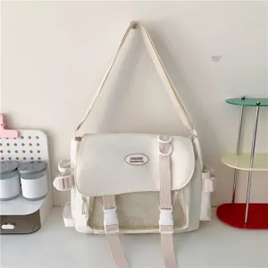 Detailed view of white canvas messenger bag with front mesh pocket and double buckle.
