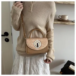 Vista detallada del bolso de mano marrón de charol de moda con cierre redondo para mujeres.