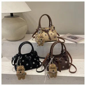 Close-up van stijlvolle stippen handtassen met schattige puppy sleutelhangerbedels.