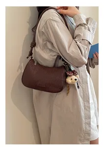 Detailed view of dark brown woven shoulder bag with cute bear pendant for women