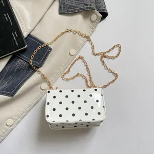 Detailed close-up shot of a chic white polka dot shoulder bag featuring a classic gold chain.