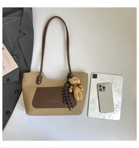 Detailed view of chic retro contrast tote bag featuring a cute plush bear pendant and pocket.