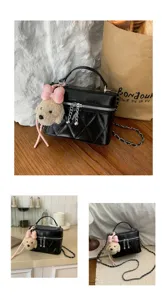 Detailed view of black quilted vanity crossbody bag featuring cute plush puppy pendant.