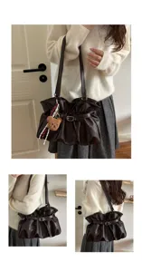 Detail view of dark brown ruched shoulder bag with belt buckle and cute bear charm.