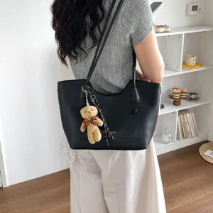 Black leather tote bag detail, casual commuter shoulder bag with cute bear pendant.