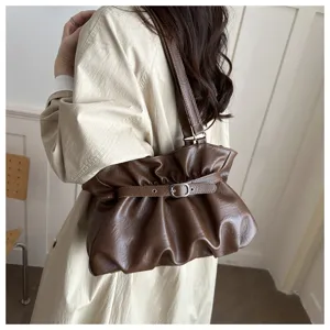 Detailed close-up of the stylish brown pleated shoulder bag, showing its unique strap and leather.