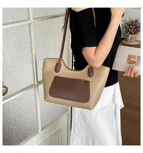 Detail view of stylish two-tone tote bag, featuring a front pocket and shoulder strap.