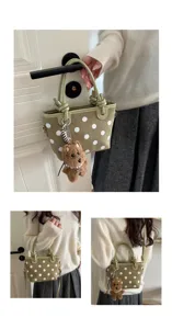Vue détaillée du sac seau rétro à pois verts avec un charmant porte-clés chien en peluche.
