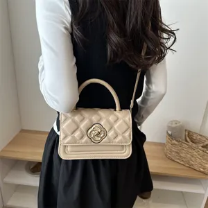 Detail van de elegante gewatteerde kinder schoudertas in beige met stijlvolle metalen slot.