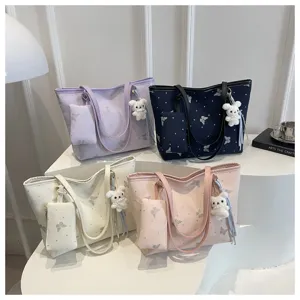 Detailed view of fashionable tote bags with cute bunny pendants and pouches in multiple colors.