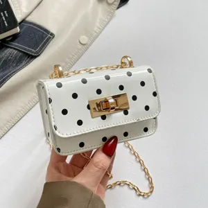 Detailed closeup view of the white polka dot mini crossbody bag with gold lock and chain.