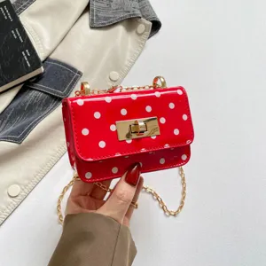 Red polka dot shoulder bag detail showing glossy patent finish, gold chain strap, and lock.