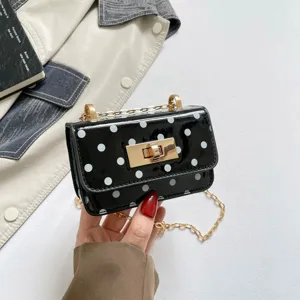 Close-up view of a stylish black patent leather polka dot mini shoulder bag with gold chain.