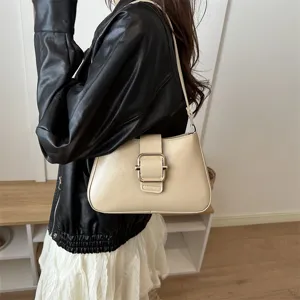 Dettaglio della borsa a baguette beige alla moda sotto l'ascella con elegante fibbia in metallo.