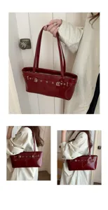 Red patent leather shoulder tote bag with vintage belt buckle design for daily commuting.