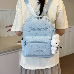 Detailed view of light blue travel backpack featuring starry pattern and cute plush bunny charm.