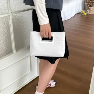 Vista dettagliata della borsa da donna bianca e strutturata con manico elegante.