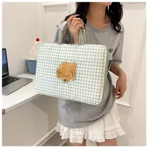 Vista dettagliata della simpatica custodia per laptop a cuadros verdi con cagnolino ricamato.