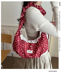 Vista dettagliata di una borsa a spalla rossa con stampa floreale, volant e bordo in pizzo.