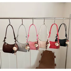 Chic woven shoulder bag for women with cute bear pendant and stylish handle design details.
