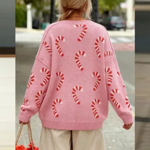 Gedetailleerd uitzicht op een roze damestrui met oversized gebreid patroon en kerststokjes.