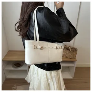 Close-up of stylish white shoulder tote bag with chic belt and rivet details, great view.