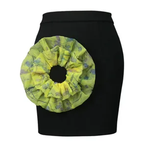Detailed view of women black pencil skirt featuring a striking yellow-green ruffled floral accent.