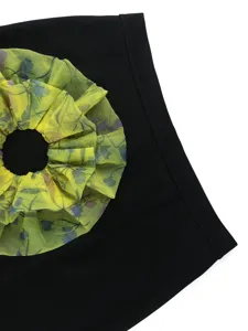 Close-up detail of the black pencil skirt featuring vibrant yellow sheer floral contrast splicing.