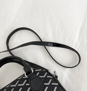 Detailed shot of black PU leather handbag strap and chevron pattern design, high quality.