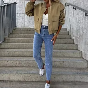 Outdoor detail shot of casual khaki bomber jacket with flap pockets worn on concrete stairs.