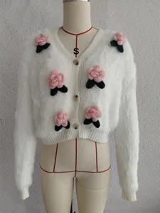 Nahaufnahme des weissen flauschigen Strickcardigans mit niedlichen rosa 3D Rosen und Knöpfen.