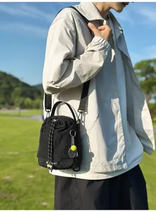 Black nylon crossbody shoulder bag detail with convenient drawstring and sporty tennis pendant.