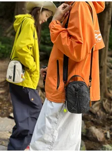 Outdoor lifestyle detail view of a stylish crossbody messenger bag worn by a model in nature.