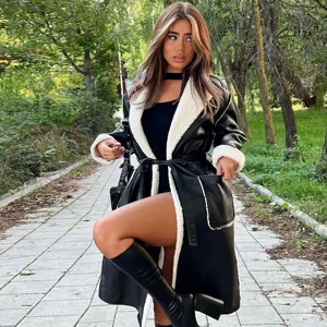 Detailed shot of a stylish black faux leather trench coat with warm white shearling lining.