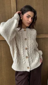 Close-up detail van dames retro grove kabel gebreid cardigan trui in romige wit.