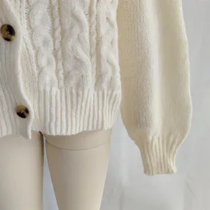Kabelvest detailweergave, gebroken witte geribbelde zoom en stijlvolle ballonmouwen.