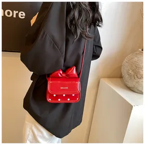 Detailed view of a cute red patent leather crossbody bag with bow and white polka dots.