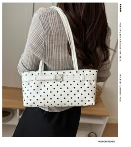 Detailed view of women's white polka dot underarm shoulder bag with stylish belt buckle design.