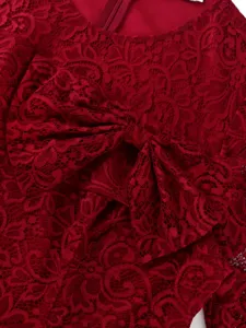 Gros plan détaillé d'une robe en dentelle rouge avec un nœud élégant et un motif floral délicat.