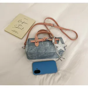 Detalle del bolso Boston de mezclilla con correas de cuero rosa y colgante de estrella.