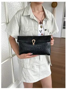 Zwarte geweven clutch voor dames, enveloppe tas met gouden metalen sluiting voor dagelijks gebruik.
