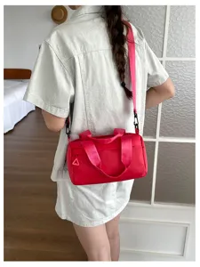 Vista detallada del elegante bolso cilíndrico rosa llevado cruzado con diseño de correa.