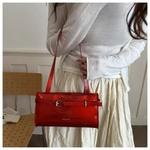 Red patent leather shoulder bag detail, stylish glossy underarm bag with chic metal buckle.