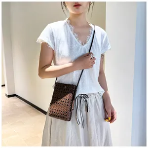 Vue détaillée d'un mini sac bandoulière en cuir tressé marron porté par un mannequin.