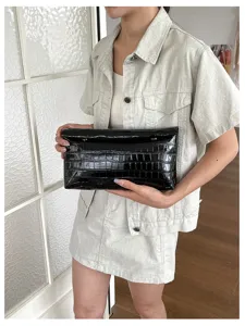 Black crocodile pattern faux leather clutch bag, detailed close-up shot showing texture.