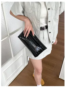 Black crocodile embossed clutch bag detail shot, elegant women's fashion accessory for work.