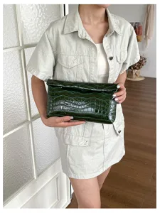 Dark green glossy crocodile pattern clutch bag for women, elegant minimalist fashion style.