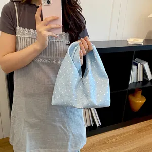 Vue detaillee du sac a main en tissu bleu clair avec pois blancs et design souple plisse.