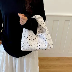 Détail de sac à main en tissu à pois avec design nuage plissé doux et poignée confortable.