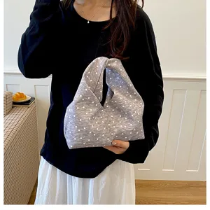 Gros plan du sac à main en tissu à pois gris, mettant en valeur la texture douce et la poignée.